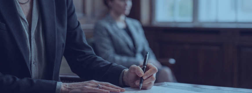 Mujer con traje negro firmando informe pericial en un despacho jurídico con fondo difuminado, representando la importancia de la pericia judicial y la solvencia técnica en derecho sanitario.
