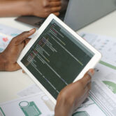 High angle shot of unrecognizable male hands holding white tablet with codes on screen