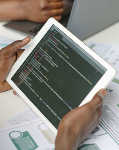 High angle shot of unrecognizable male hands holding white tablet with codes on screen
