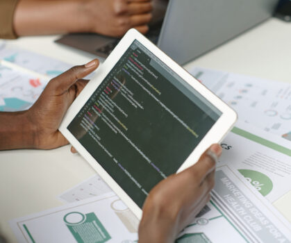 High angle shot of unrecognizable male hands holding white tablet with codes on screen