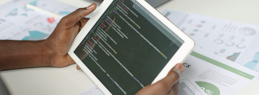 High angle shot of unrecognizable male hands holding white tablet with codes on screen