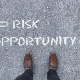 "Risk" and "Opportunity" with arrows pointing to the left and right side Top view on a man standing in front of the words "Risk" and "Opportunity" with arrows pointing to the left and right side of the picture