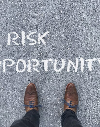 Top view on a man standing in front of the words "Risk" and "Opportunity" with arrows pointing to the left and right side of the picture
