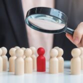 Businesswoman hand holding magnifying glass for recruiting leade Businesswoman hand holding magnifying glass for recruiting leader man wooden from crowd of employees.Human resource management, Recruitment, Teamwork, hiring and leadership Concepts